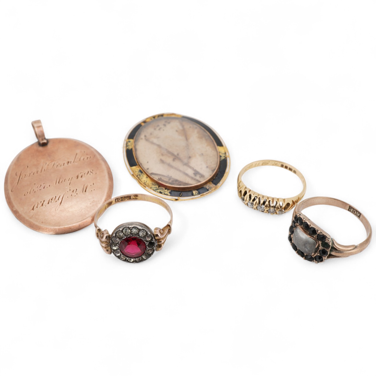 A George V 18ct gold and graduated claw set five stone diamond ring, size K, together with a 9ct and two colour paste set ring, a 19th century mourning ring, with plaited hair and an George III yellow metal and enamel mo